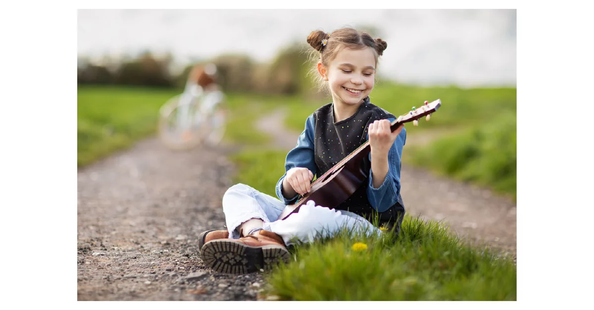 a young child plays a ukulele